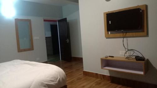 佩林Mandavya homestay的一间卧室配有一张床和一台平面电视