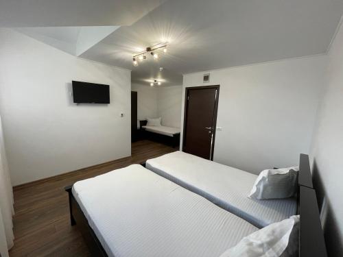 MioveniDr House的一间卧室设有两张床,墙上配有电视。