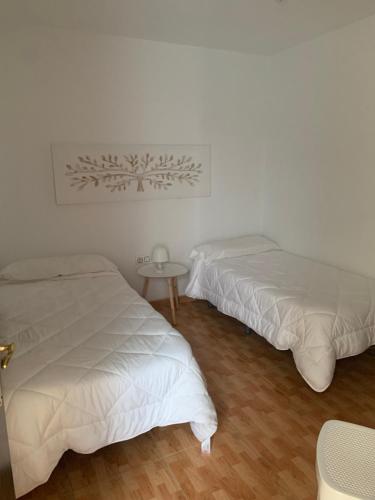 科尼尔-德拉弗龙特拉Apartahotel Playa Conil的白色客房的两张床和一张桌子