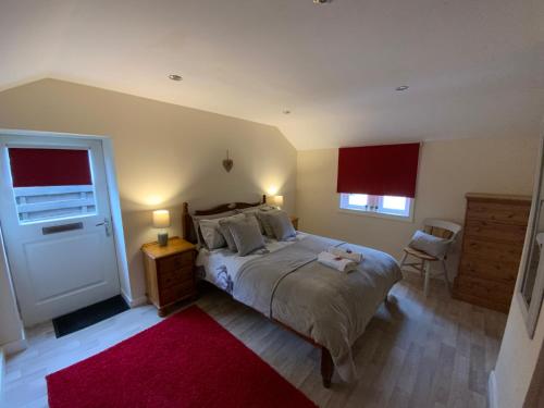 Kincardine OʼNeilDeeside Snugs Apartments的一间卧室配有一张大床和红色地毯。