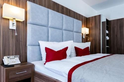 库洛特拉森STEIGER Hotel Rathener Hof的一间卧室配有一张带红色枕头的大床