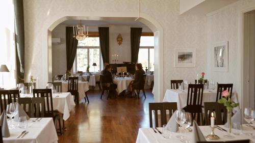 Sandöverken伯爵库登斯酒店 & 餐厅的餐厅设有白色的桌椅,而客人则坐在桌子旁