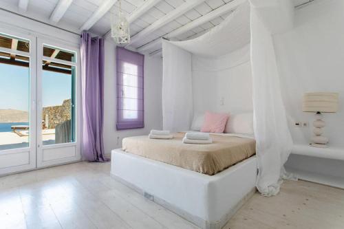 帕诺尔莫斯米科诺斯Villa ANASA private Pool & Jacuzzi 8pax at Panormos的一间白色的卧室,配有一张床,享有海景