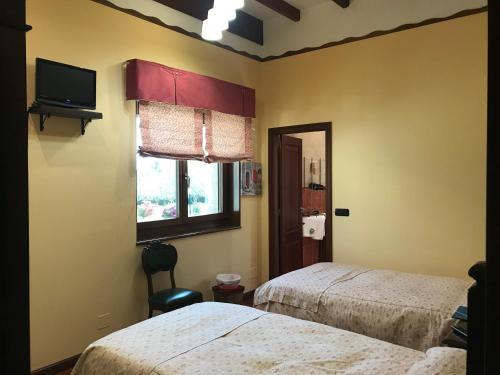 比拉尔瓦Hotel Batán的一间卧室设有两张床、一台电视和一扇窗户。