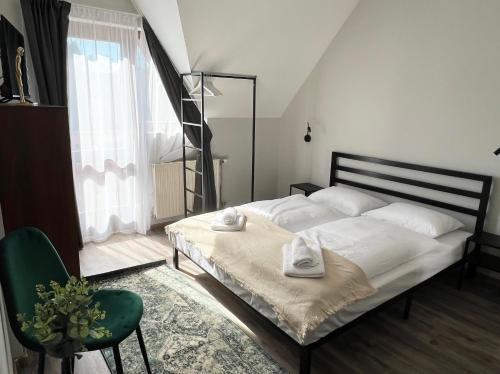 凯斯特海伊Nussbaum Panzió的卧室配有白色的床和绿色椅子