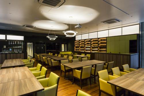 东京龙名馆酒店御茶水总店的餐厅设有木桌和黄色椅子