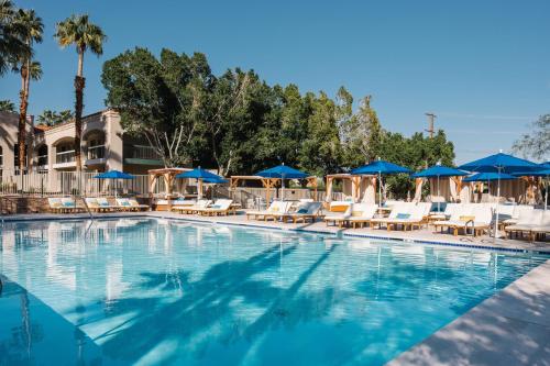 棕榈泉L3 Oasis Hotel的一个带椅子和蓝伞的游泳池