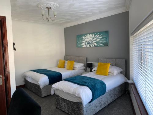斯旺西Cosy 2 Bed Flat 1 in Swansea - Home away from Home的小客房内的两张床,配有黄色和蓝色枕头