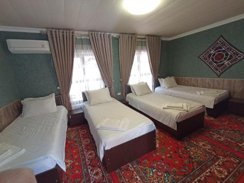 撒马尔罕OQSAROY SAMARKAND Guest House的带三张床和地毯的房间