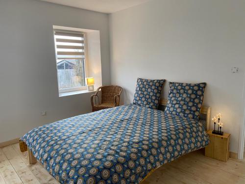MazayeLa Bulle du Quinze的一间卧室配有一张带蓝色棉被的床和窗户。