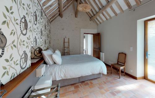 谢韦尔尼Le Petit Pavillon的一间卧室配有一张大床和一把椅子
