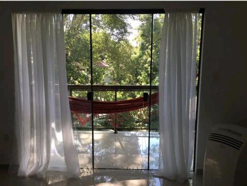 阿布拉奥Ohana suíte Abraão - Ilha Grande的窗户配有白色窗帘,享有庭院的景致