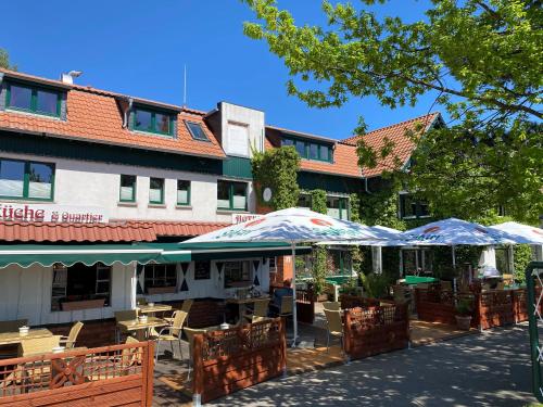 宾茨Oma's Küche & Quartier的大楼前的餐厅,配有桌子和遮阳伞