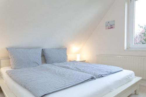 提努姆Haus Lia Rechts App 5的一张带蓝色床单的白色床和窗户