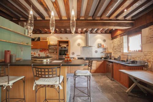 康布勒梅尔Locations - Domaine Le Coq Enchanté的大型厨房设有木制天花板和桌椅