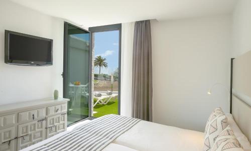 英格兰海滩朵涅罗萨别墅酒店的一间卧室设有一张床和一个滑动玻璃门