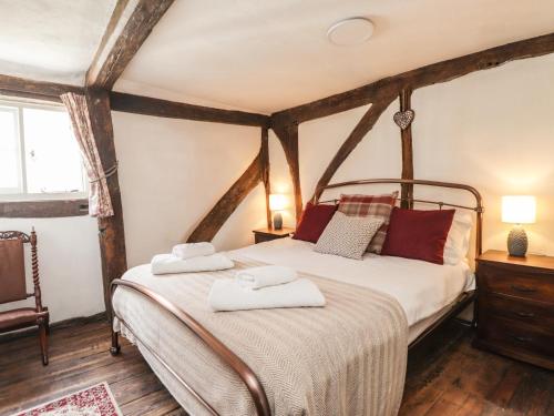 桑德维奇Tudor Cottage的一间卧室配有一张床,上面有两条毛巾