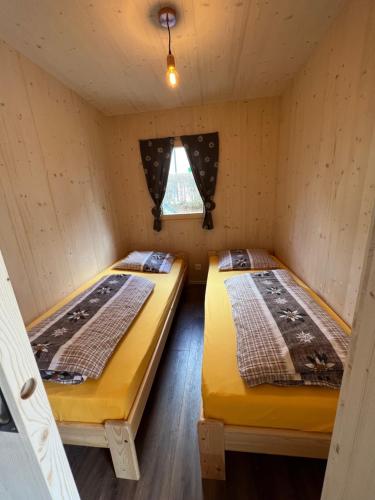 波斯基亚沃Bungalow Miralago in Camping Cavresc, Via dal Cavresc 1, 7746 Le Prese-Poschiavo的小屋内的两张床,设有窗户