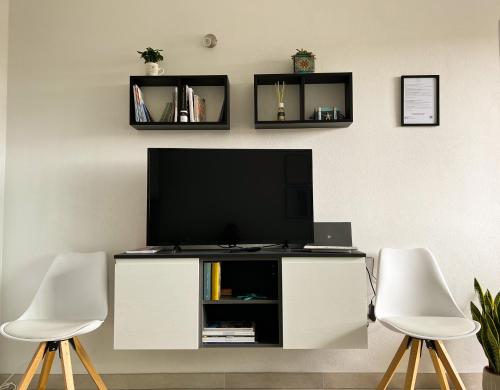 托里格兰德Sunnyside Apartment的客厅配有电视和2把白色椅子