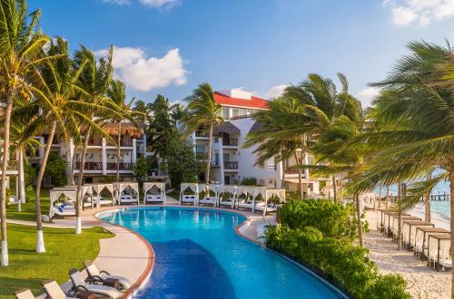 莫雷洛斯港Desire Riviera Maya Pearl Resort All Inclusive - Couples Only的享有带游泳池和棕榈树的度假村的景致