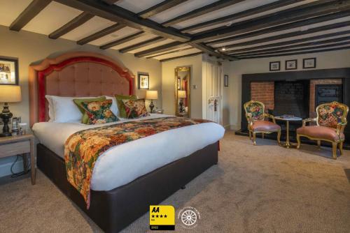 图克斯伯里The Tudor House Hotel, Tewkesbury, Gloucestershire的一间卧室配有一张大床和一张桌子及椅子