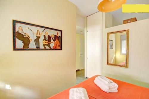 特拉维夫TLV Living Apartment的一间卧室配有橙色的床,墙上挂着一幅画