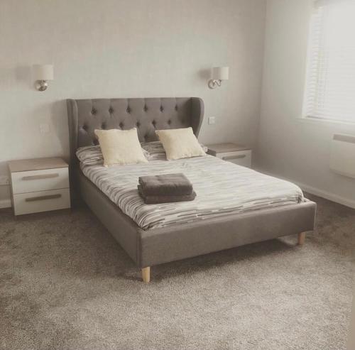 威克Wick Holiday Home - NC500 Route的一间卧室配有一张带灰色床头板的床
