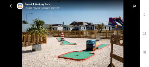 Saint OsythJacqueline's holiday homes seawick clacton on sea的一个带两个游戏设备的沙地游乐场