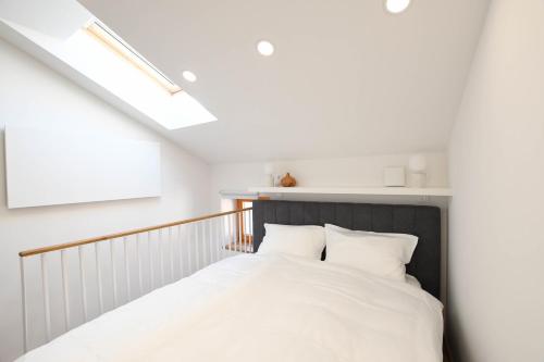 皮兰BAY BREEZE Holiday house in Piran的一间卧室配有一张带白色床单和天窗的床。