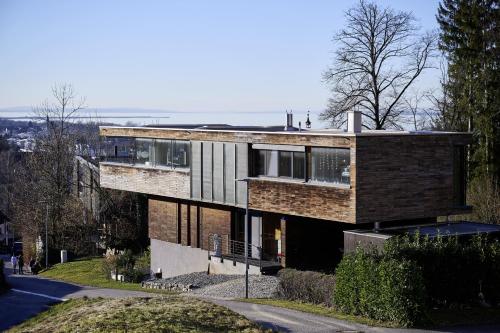 布雷根茨Design Apartment mit Naturblick的山丘上一所砖房子,有街道