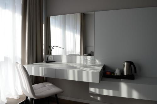 米什科尔茨Premier Hotel Miskolc的白色的厨房配有白色的柜台和椅子