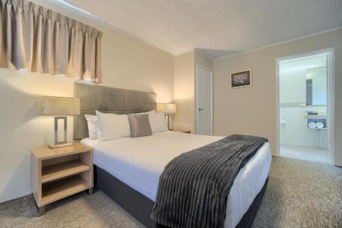 奥尔巴尼Albany Motel & Apartments的一间卧室配有一张大床和一个带四柱床的床头柜。