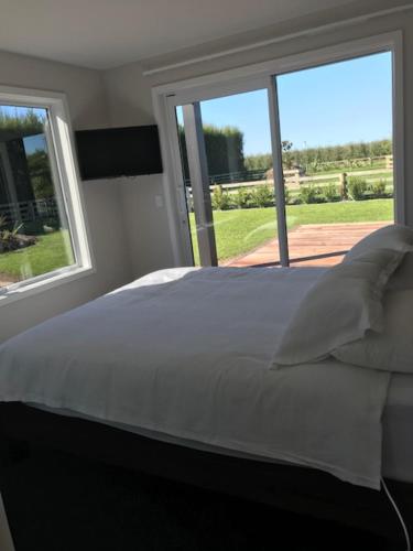 哈士汀Dunray Cottage - Welcome to Havelock North的卧室配有白色的床和2扇窗户。
