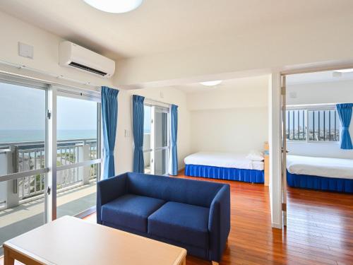 石垣岛Daily & Weekly Condominium BLUE OCEAN ISHIGAKI的带沙发和床的客厅以及阳台。