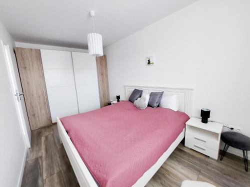 克塞洛Juhar Apartman的白色卧室配有粉红色的床和书桌