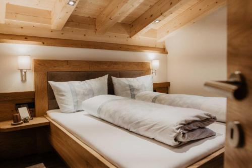NavisFerienhaus Bergler Hoamat的卧室配有一张白色大床和木制天花板