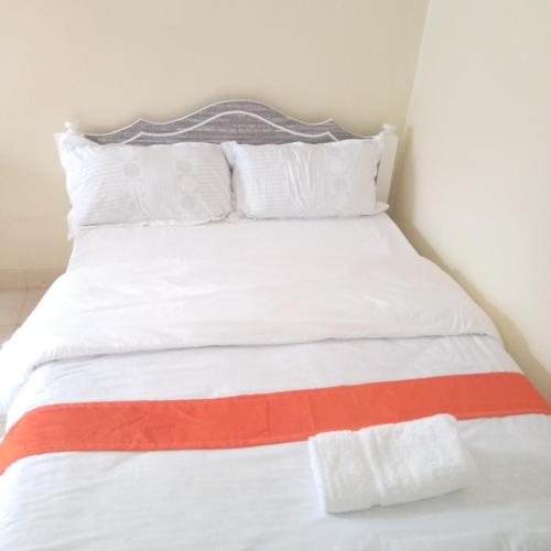 奈瓦沙Luna Light Guest House的白色的床,配有橙色和白色的枕头