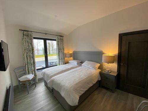 恩尼斯基林Tullybay Holiday Lodges的一间卧室设有一张大床和一个窗户。