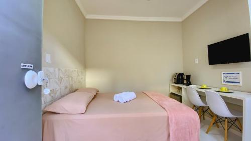 伊列乌斯Kalug - Suíte CASAL independente em Guest house的客房设有一张粉红色的床、一张书桌和一台电视。