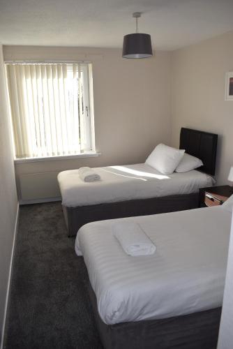 福尔柯克Kelpies Serviced Apartments- Abbotsford的酒店客房设有两张床和窗户。