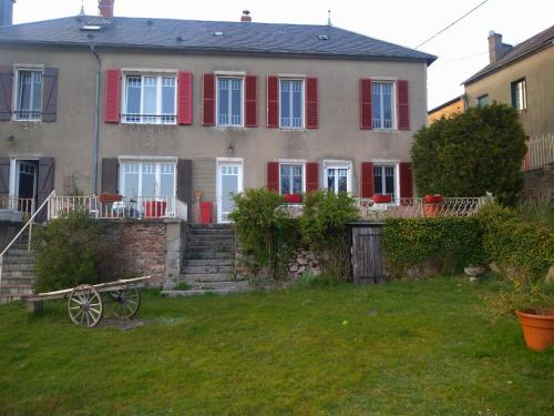 Moux-en-MorvanMaison Haute的一座带红色百叶窗和庭院的大房子