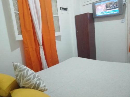 马德普拉塔La Casona-Hotel的一间设有白色桌子和电视的客房