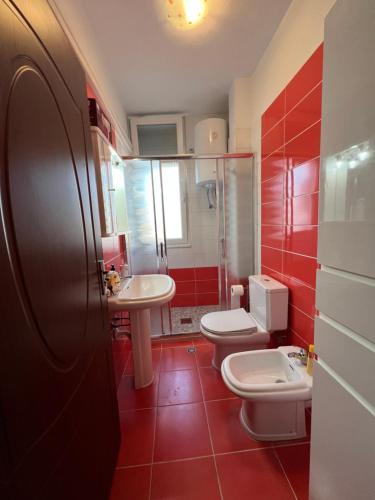 斯库台City Center Apartment in Shkoder的红色的浴室设有两个卫生间和水槽