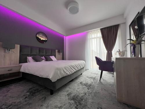 百乐费利克斯Majestic Boutique Hotel的紫色客房配有一张床和一张书桌