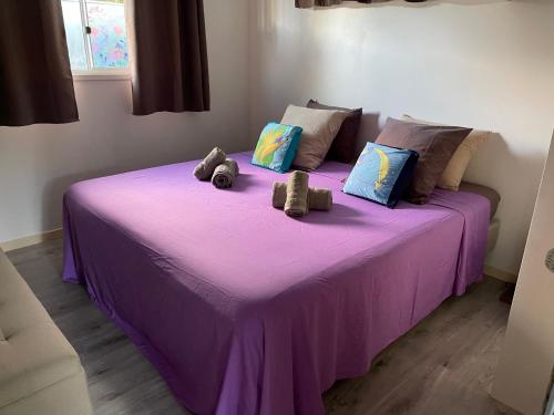 乌图罗阿bungalow chez sofpat的紫色的床,上面有两只填充的动物