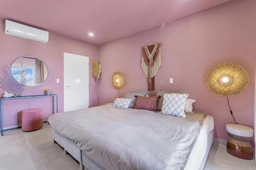 克拉伦代克Apartment Turtle at Windsock Beach的一间卧室设有一张大床和粉红色的墙壁