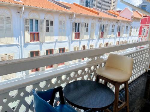 新加坡Hotel Calmo Chinatown的阳台配有桌椅,设有建筑