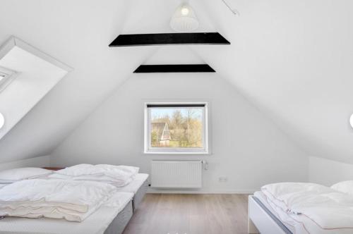霍伊斯莱乌Lundø的白色客房的两张床,设有窗户