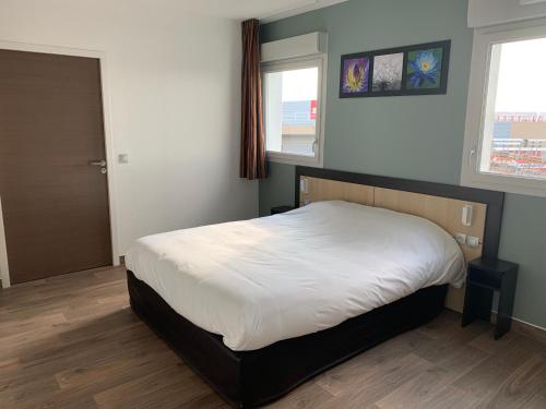塞纳河畔罗米伊B&B HOTEL Romilly-sur-Seine的一间卧室设有一张床和两个窗户。