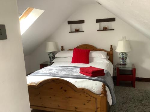 斯旺西The Old Stables的一间卧室配有一张带红色枕头的木床
